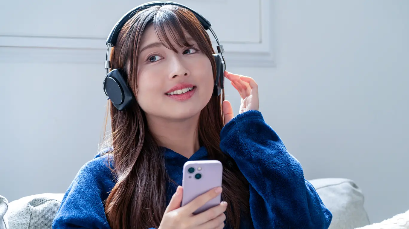 女性がヘッドフォンをして音楽を聴いている